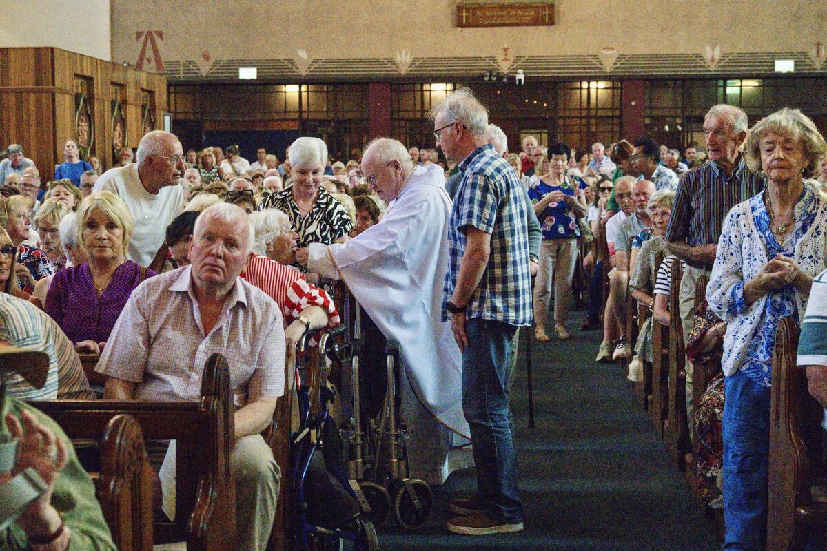  Father Paddy O’Reilly bringing Holy Communion to members of the congregation in St Augustine’s Church as many were unable to reach the altar in the packed church. Picture: Chani Anderson