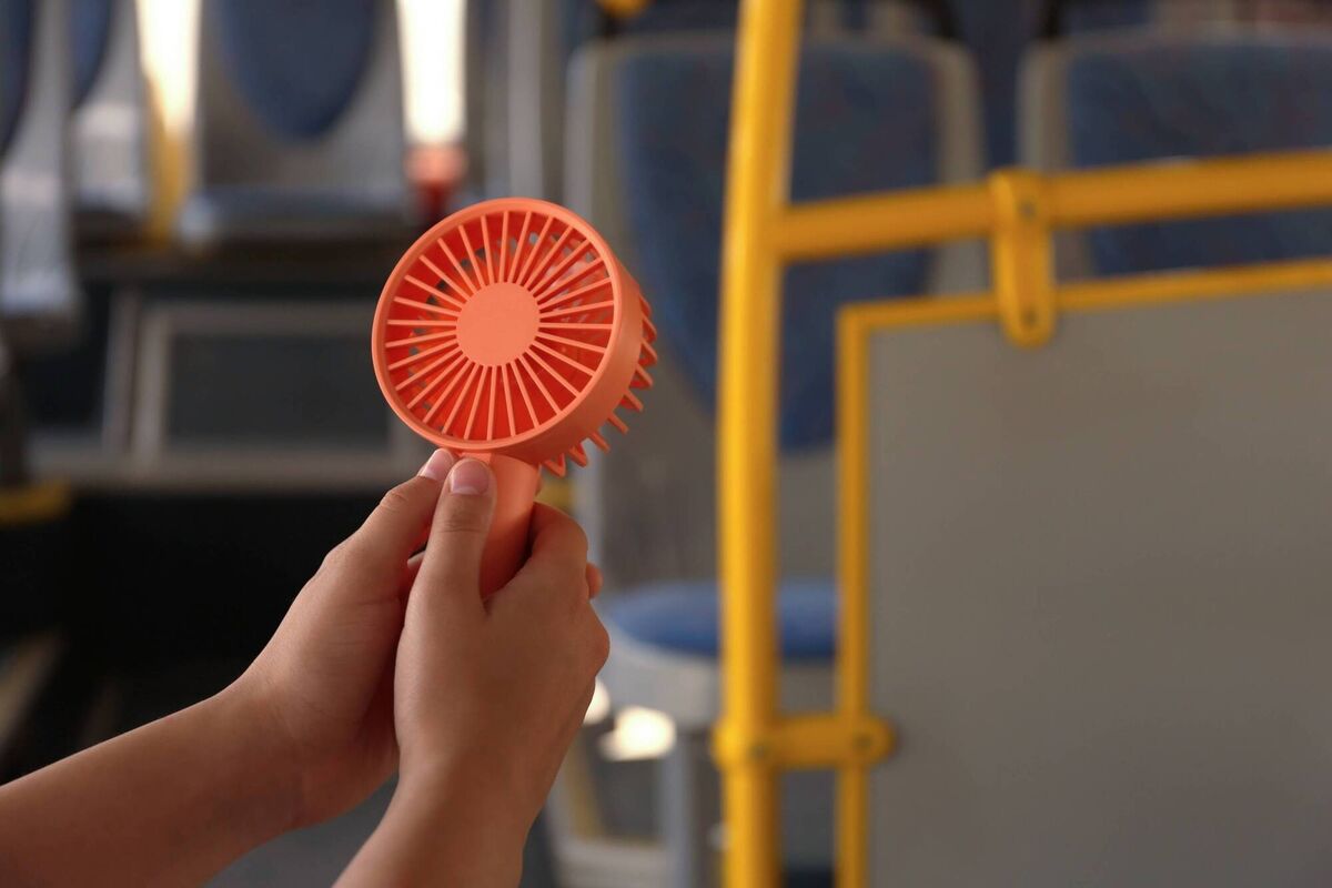 A discreet electric fan is probably fine to use in public, even on a packed bus.