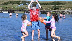<p>Tom Kingston, Kinsale 'cools off' with the help of his cousins Sarah, Billy and Anna Ryan, from Tipperary. Met Éireann has issued a further high temperature warning which comes into effect today. Picture: Larry Cummins</p>