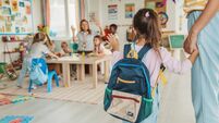 Preschool teacher in classroom greeting new student