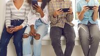Children sitting on windowsill and ignoring real life immersed in their cell phones