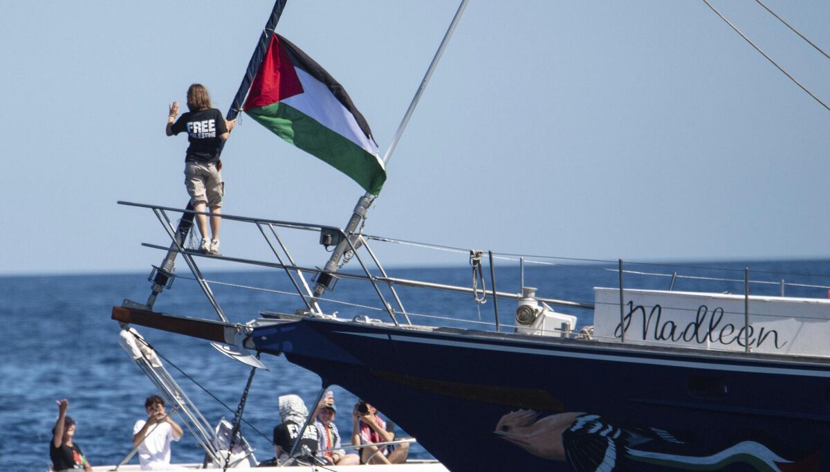 Climate activist Greta Thunberg stands near a Palestinian flag after boarding the Madleen boat and before setting sail for Gaza along with activists of the Freedom Flotilla Coalition, departing from the Sicilian port of Catania, Italy, Sunday, June 1, 2025. (AP Photo/Salvatore Cavalli)