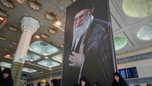 Women sit beneath a portrait of the late Supreme Leader Ali Khamenei (Vahid Salemi/AP) Women sit beneath a portrait of the late Supreme Leader Ali Khamenei (Vahid Salemi/AP)