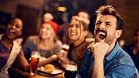 Sports fan and his friends watching a match on TV in a pub.