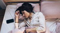 Technology-Aided Sleep: Woman in Pyjamas Listening to Relaxing Music on Her Smartphone in Bed in the Morning