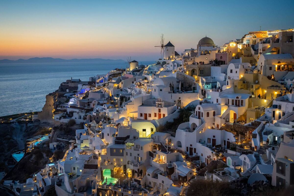 Beautiful sunset cityscape landscape view illuminated city lights Town of Oia at night in Santorini Island