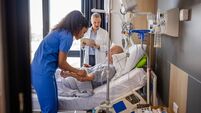 Senior man receiving medical care in hospital with healthcare professionals assisting in recovery process