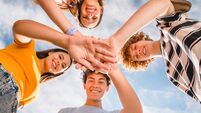 Low angle view of smiling boys and girls in casual giving high five stacking hands together outside
