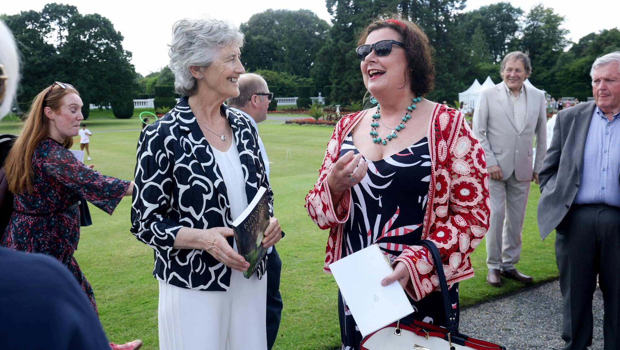 President Catherine Connolly (left) and Jillian Godsil (right) at a garden party in Áras an Uachtarán where the President mingled freely among the guests, speaking with warmth and humour.