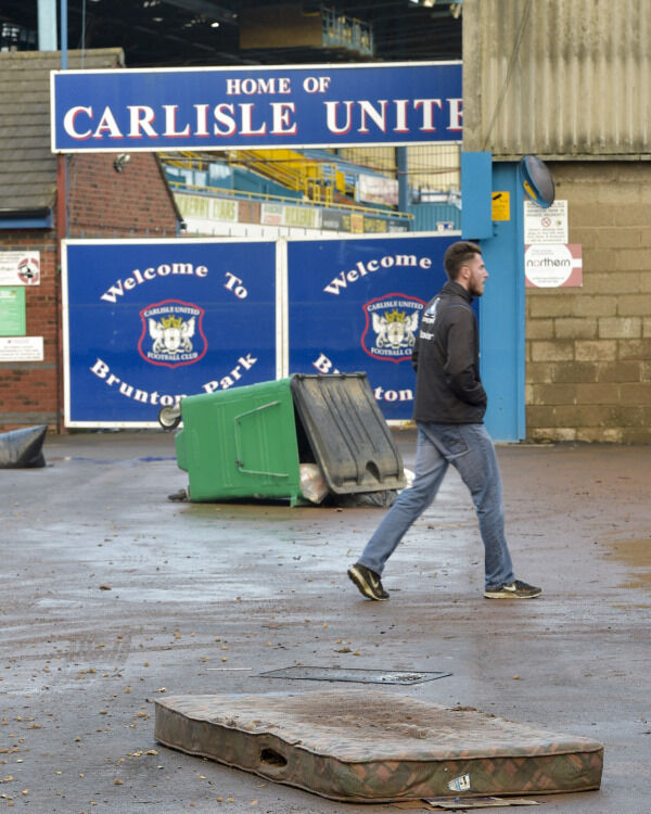 A man walks past storm debris outside Brunton Park, the Carlisle United stadium, as the clean-up begins after the floods in Carlisle. Photo: Ben Birchall/PA