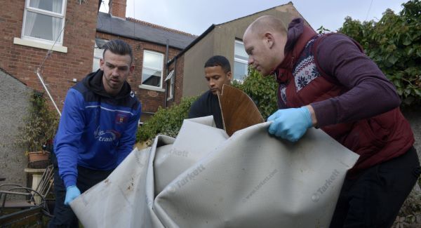 Carlisle United footballers (left to right) Michael Raynes, Joe Thompson and Jason Kennedy help to clear items from a flood-damaged home in Carlisle as the club's players offered help to people affected by Storm Desmond. Photo: Ben Birchall/PA