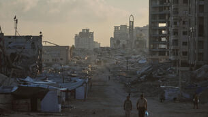 <p>Palestinians walk along a street surrounded by buildings destroyed in Israeli military strikes during the Israel-Hamas war, in Gaza City. Picture: Jehad Alshrafi/AP</p>