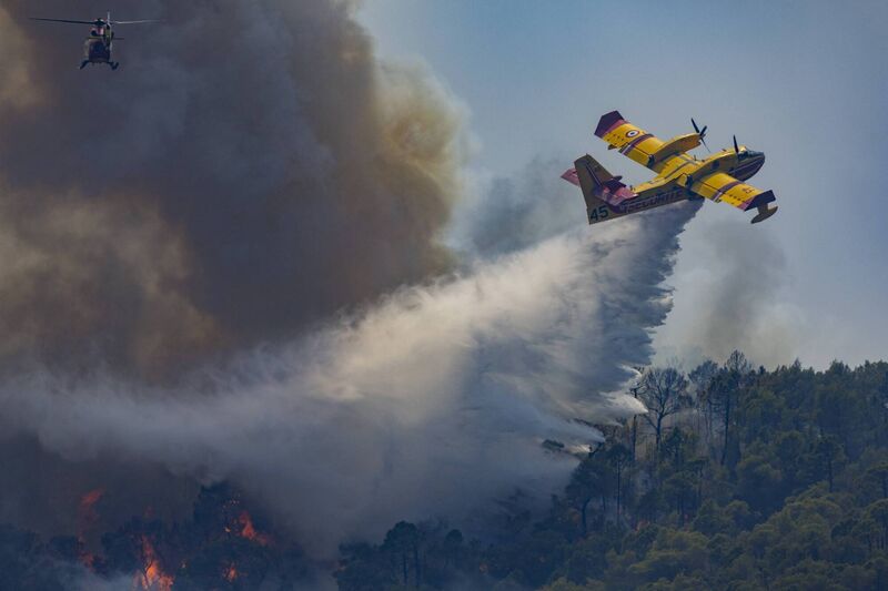 A Canadair water bomber drops water on an advancing wildfire as a firefighting helicopter flies above thick smoke near Cotignac, Var, France, July 23, 2026. Picture: Thibaut Durand / Hans Lucas / AFP via Getty Images