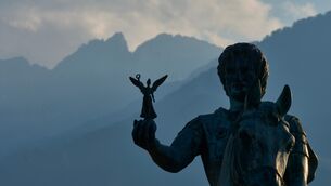 A statue of Alexander the Great holding Nike, the Greek goddess of victory, backdropped by Mount Olympus’ highest peaks, Mytikas and Stefani (Petros Giannakouris/AP)