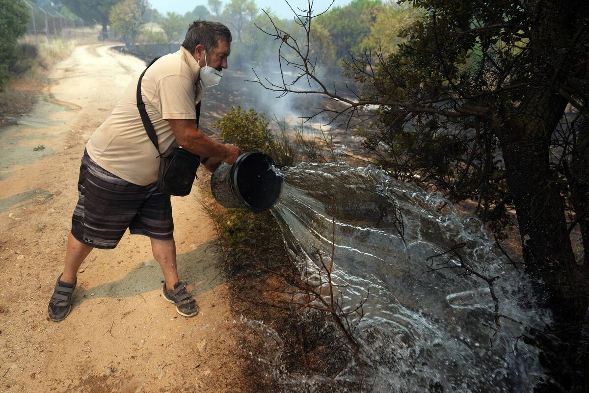 A resident throws water to put out a fire at his land during a wildfire near San Martin de Valdeiglesias, about 70 kilometers west of Madrid, on July 26, 2026. (Photo by Cesar MANSO / AFP via Getty Images) A resident throws water to put out a fire at his land during a wildfire near San Martin de Valdeiglesias, about 70 kilometers west of Madrid, on July 26, 2026. (Photo by Cesar MANSO / AFP via Getty Images)