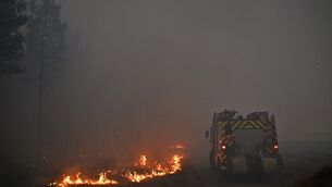 A fire engine drives through smoke of a wildfire raging near Marcheprime (Emma Da Silva/AP)