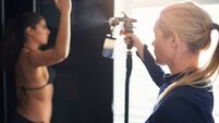 Beautician spraying tan on woman in salon