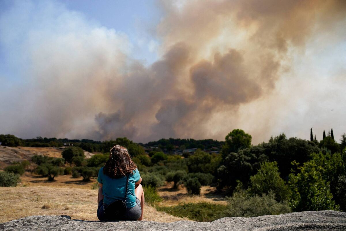 A woman looks as smoke rises from a wildfire in San Martin de Valdeiglesias, Community of Madrid, Spain, July 26, 2026. REUTERS/Ana Beltran