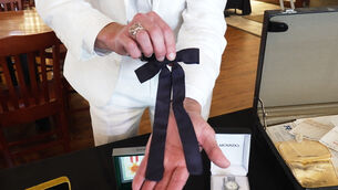 Auctioneer Jonathan Klunk shows a black bow tie worn by KFC founder Harland Sanders (Dylan Lovan/AP)