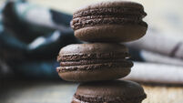 Fresh baked chocolate macarons on wooden texture