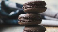 Fresh baked chocolate macarons on wooden texture