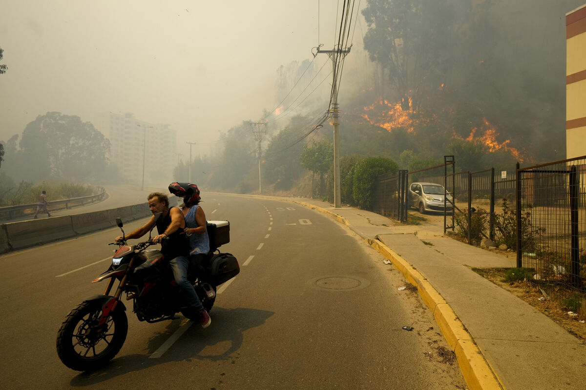 Residents evacuate on a motorcycle as smoke caused by forest fires fills the sky and flames spread into Vina del Mar, Chile, in February 2024. File picture: Esteban Felix/AP Residents evacuate on a motorcycle as smoke caused by forest fires fills the sky and flames spread into Vina del Mar, Chile, in February 2024. File picture: Esteban Felix/AP