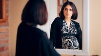Introspective Pregnant Woman Analyzing Herself in a Mirror