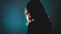 silhouette of depress woman standing in the dark with light shine behind