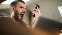 iStock-1426137405.jpg Angry man yelling while using cell phone while working at home.