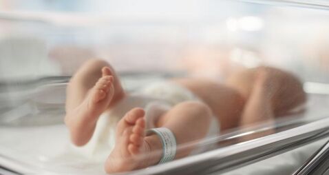 Cute Little Caucasian Newborn Baby Lying in Bassinet in a Maternity Hospital. Portrait of a Tiny Playful and Energetic Child wit