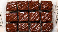 1987938912 Cut peaces of dark chocolate moist buttermilk sheet cake with chocolate butter cream, homemade dessert on a cookig resting tray