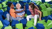 Three multiracial children play in pool of foam blocks