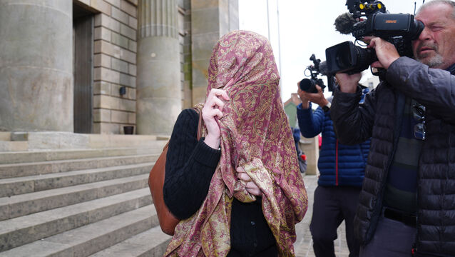 <p>Isobella Perrie Sullivan covers up as she leaves Monaghan District Court on Friday (Brian Lawless/PA)</p>