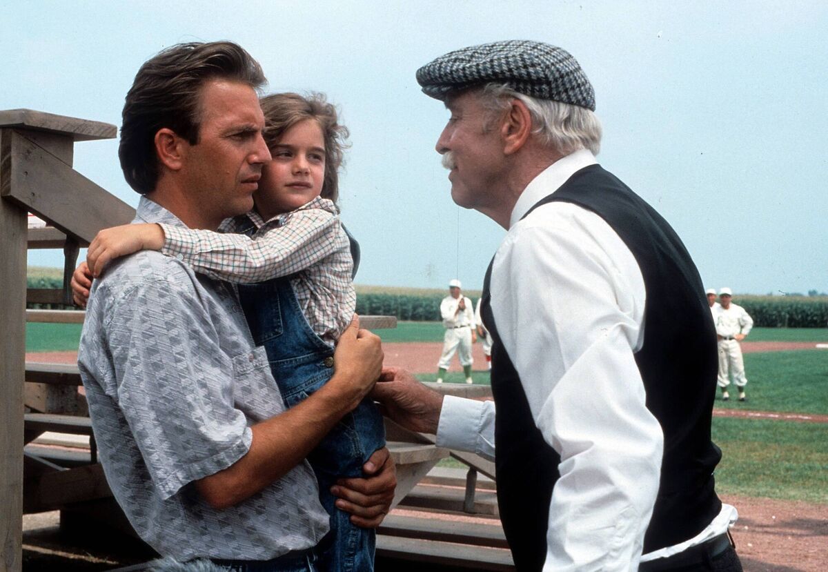 Kevin Costner holding Gaby Hoffmann in a scene from 'Field Of Dreams'.
