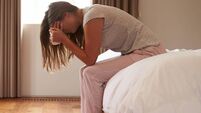 Woman Suffering From Depression Sitting On Bed And Crying
