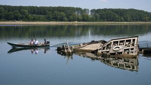 <p>People watch the wreckage of a WWII German warship, emerged due to the drought, in front of Djerdap II, a large dam on the Danube River, between Romania and Serbia, near Prahovo, Serbia, Tuesday, Aug. 4, 2026. (AP Photo/Darko Vojinovic)</p>