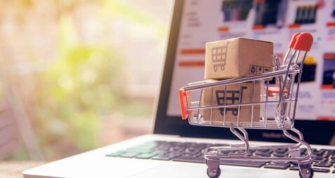 Shopping online concept - Parcel or Paper cartons with a shopping cart logo in a trolley on a laptop keyboard. Shopping service