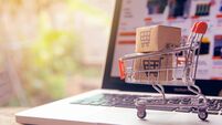 iStock-1249219777.jpg Shopping online concept - Parcel or Paper cartons with a shopping cart logo in a trolley on a laptop keyboard. Shopping service