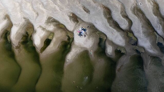 <p>A family with umbrellas on a sandbar uncovered by receding water on the Danube River near Ilok, Croatia, earlier this month. Picture: Marko Perkov/AFP/Getty</p>