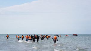 <p>People thought to be migrants wade into the sea to board a small boat off the coast of Equihen-Plage, France, during an attempt to cross the English Channel. </p>