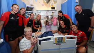 <p>Meadhbh Enright, aged 8, with the O'Duffy Cup and her parents and the Cork team during their visit to CHI Temple Street Hospital visit. Pic: ©INPHO/Ben Brady</p>