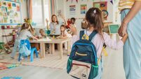 Preschool teacher in classroom greeting new student