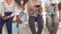 Children sitting on windowsill and ignoring real life immersed in their cell phones