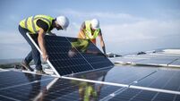 Two engineers installing solar panels on roof.