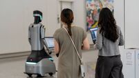 Women working on laptops with a service robot in Hong Kong International Airport