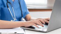Veterinarian woman in blue uniform is using laptop to searching pet information and typing treatment