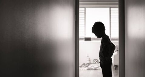Sad boy standing alone in the hallway