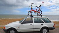 iStock-2274923578.jpg Classic white Ford Escort Mk4 with Classic Raleigh Chopper bike on roof