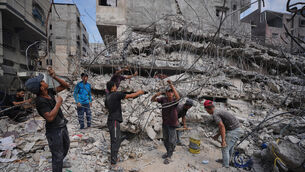 Palestinians in the rubble of buildings destroyed by Israeli airstrikes (Jehad Alshrafi/AP)