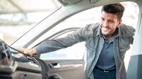 Smiling man taking taking look to car in showroom